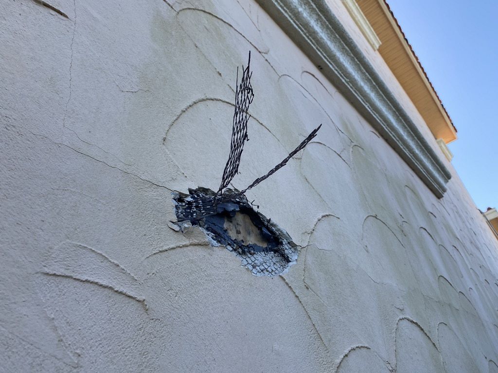 Close-up of cracked stucco damage on Florida home exterior before siding replacement