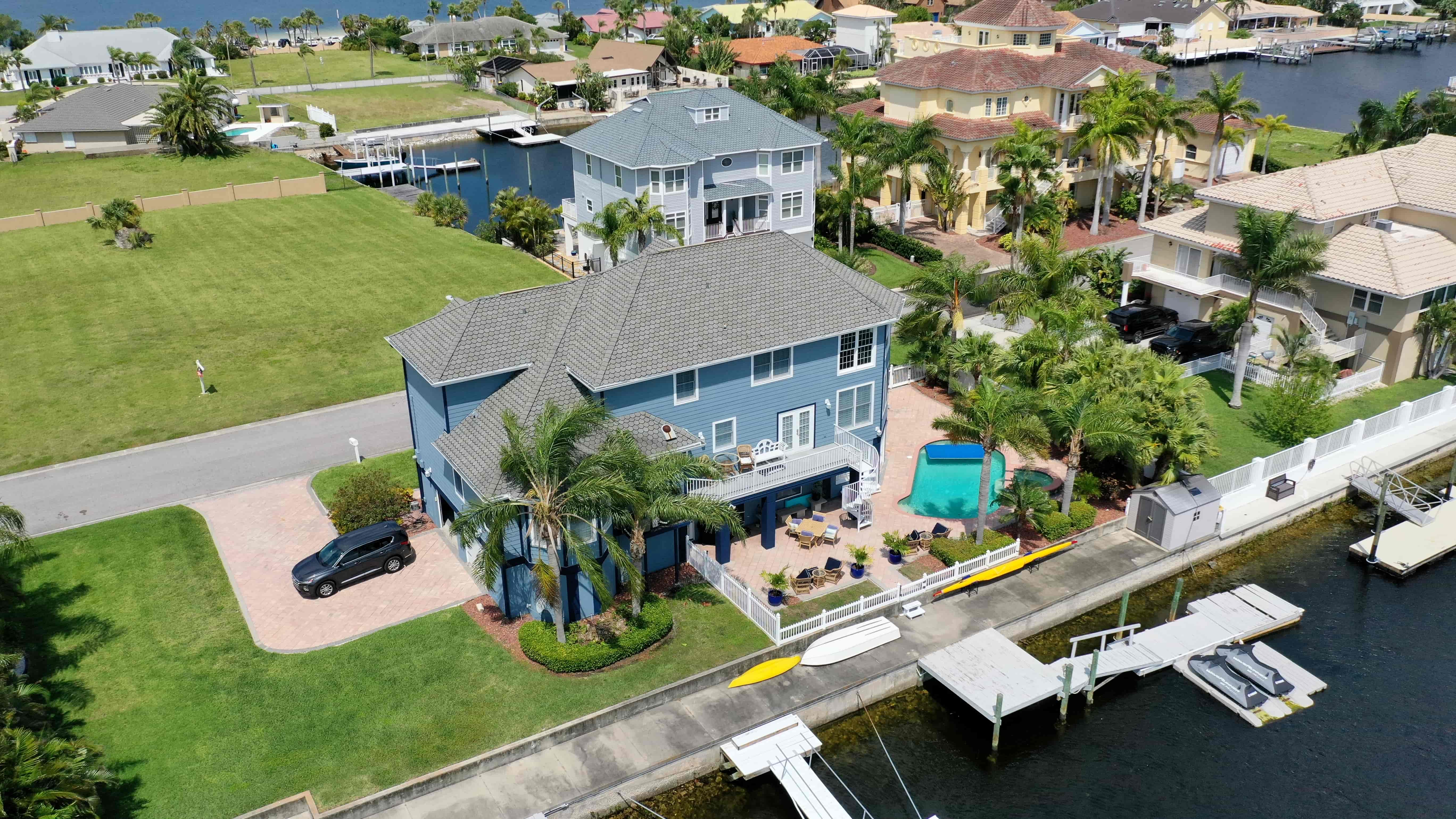 Aerial view of Florida waterfront home with new siding, backyard pool, dock, and canal access