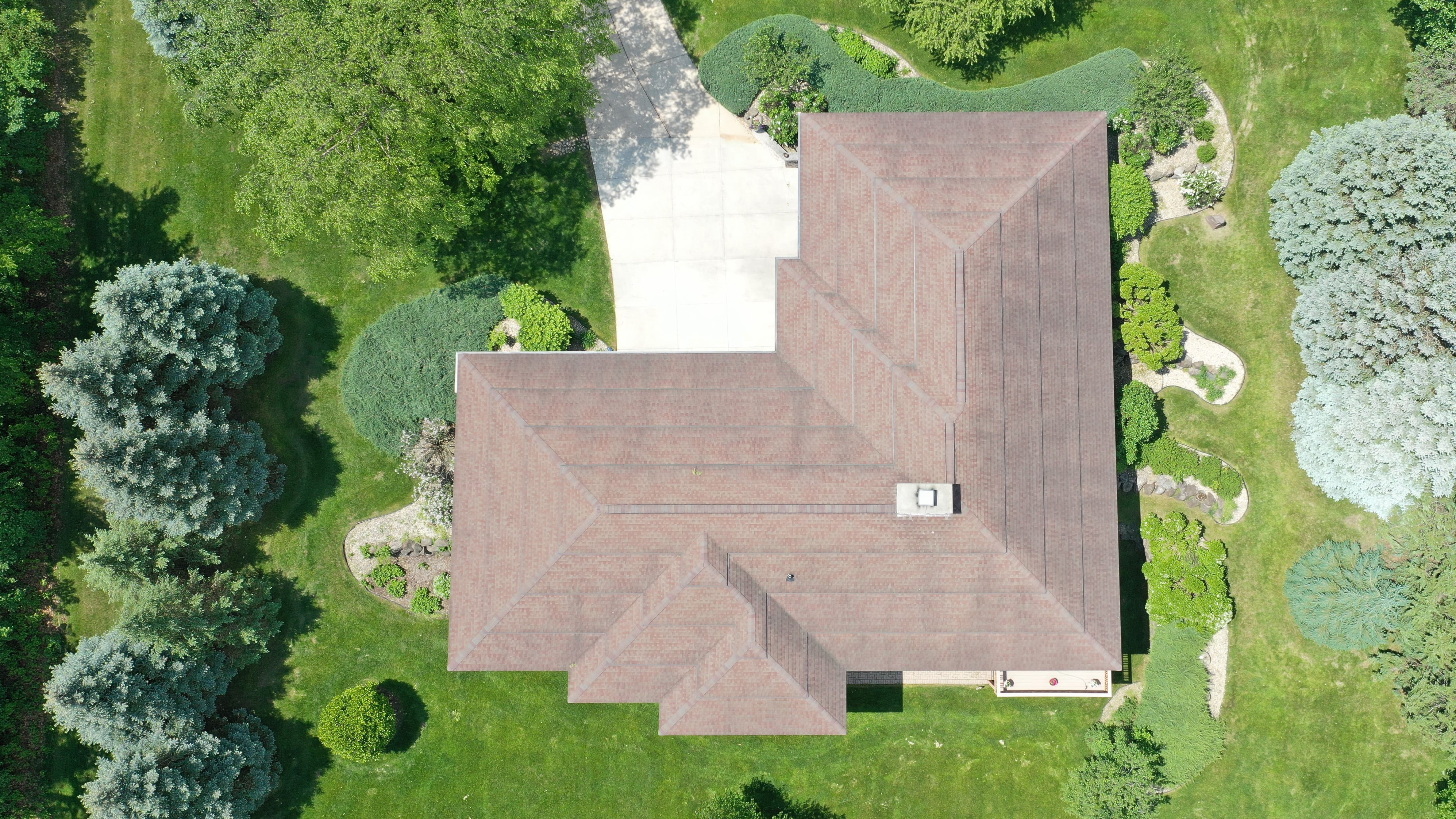 Before roof replacement in Madison WI showing aging shingles on complex stepped roof design prior to upgrade